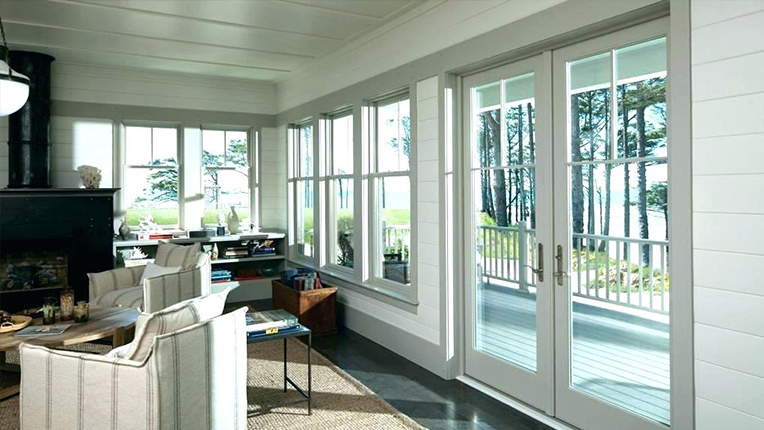 Interior view of a coastal home's living area with large windows, a patio door, and a view of the sea